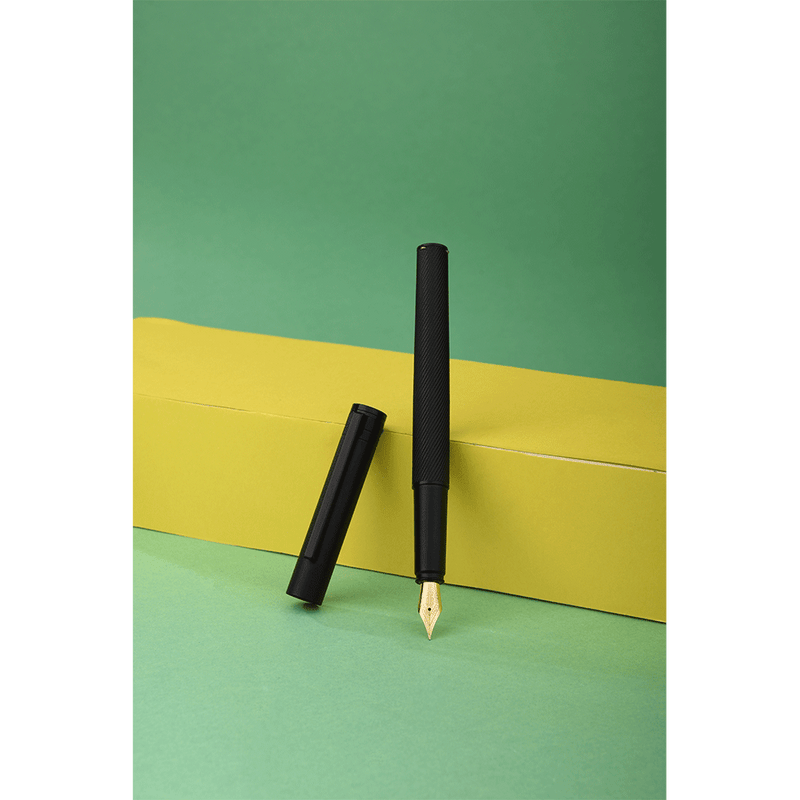 HONGDIAN H2 Black Fountain Pen Open Cap Display and Cap Beside Pen with Support of Yellow Paper Box and Light Green Background
