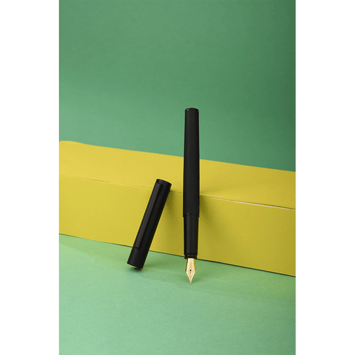 HONGDIAN H2 Black Fountain Pen Open Cap Display and Cap Beside Pen with Support of Yellow Paper Box and Light Green Background
